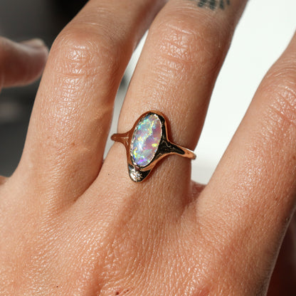 A long oval opal is bezel set in 14k gold  with  a star set  diamond at the base of the ring.